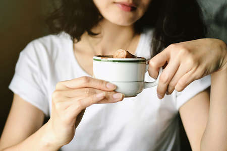 Hipster trendy girl holding a coffee mug in coffee cafe, Woman giving a hot coffee cup for energy morning start, Urban lifestyle. (Color Process) (Selective Focus)の写真素材