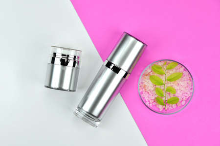 Cosmetic bottle containers with green herbal leaves, Blank label for branding mock-up, Natural beauty product concept, Flat lay on color background.の写真素材