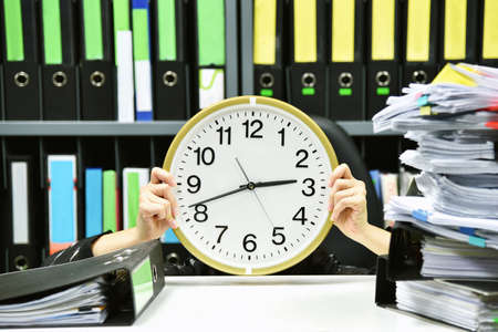Office worker holding a clock, Working overtime and lot of work, Time management concept.の写真素材