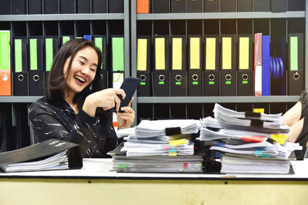 Lazy asian office woman using mobile smart phone in working time, Non productive employee.の写真素材