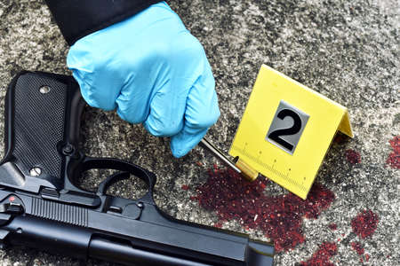 Crime scene investigation, Detective collecting bullet shell with blood stain against the crime marker.の写真素材
