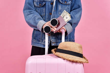 Traveler holding pink suitcase, Passenger and passport document over pink background, Money cash and travel concept.の写真素材
