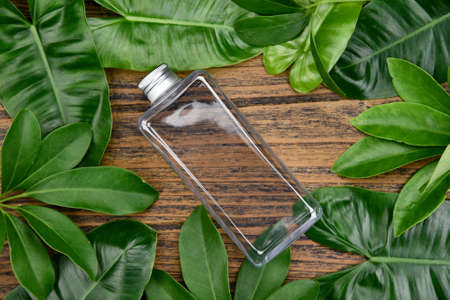 Natural skincare beauty product concept, Cosmetic bottle containers on green herbal leaves background, Blank label for branding mock-up.の写真素材