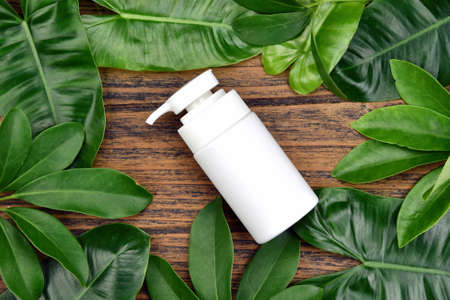 Natural skincare beauty product concept, Cosmetic bottle containers on green herbal leaves background, Blank label for branding mock-up.の写真素材