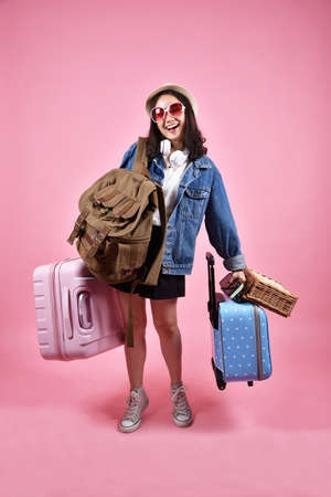 Smiling asian woman traveler carry lot of baggage, Happy tourist girl having cheerful holiday trip, Many luggage, suitcase and backpack, Bag deposit service.の写真素材