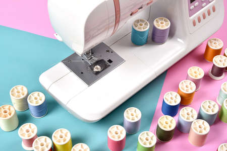 Pastel color background, Dressmaker and designer desk, Close up foot of sewing machine and handcraft accessories.の写真素材