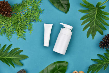 Cosmetic bottle containers on green herbal leaves background, Blank label for branding mock-up, Natural organic skincare beauty product concept.の写真素材