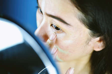 Asian woman applying cosmetics makeup and using color correction concealer, Learning doing self...