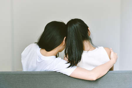 Girlfriends hugging together to encourage and support, Asian lesbian couple lean on the shoulder of each other.の写真素材