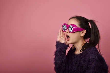 Surprised asian woman, Shouting girl wearing funny glasses on isolated pink background, Wow face feelings with copy space for advertising.の写真素材