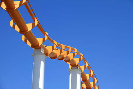 Roller coaster over clear blue sky background at amusement park, Colorful pleasure railroad track...