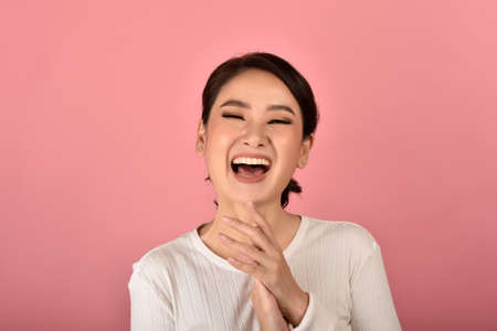 Asian woman laughing and enjoy on pink background, Portrait of happy smiling middle age woman in casual clothes looking at the camera.の写真素材