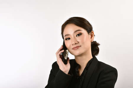 Confident expert woman secretary smiling and working at office, Asian business woman using smartphone.の写真素材
