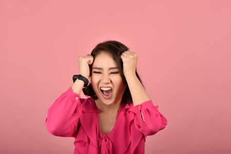 Angry asian woman, Screaming girl with furious aggressive hand gesture on pink background, Face expression and human emotion.の写真素材