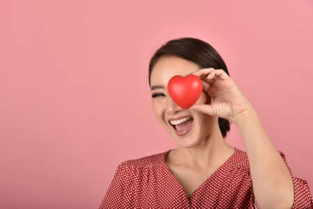 Gentle asian woman holding red heart, Happy smiling girl showing love sign to support and encourage,...