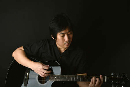 Professional musician playing acoustic guitar in music recording studio.の写真素材