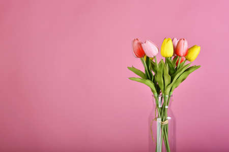 Tulip flowers bouquet for celebration on pink background. Artificial tulips arrangement in vase.の写真素材