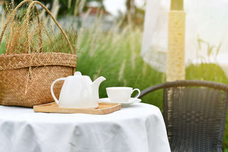 English tea time in garden, Relaxing time with favorite drink, Cup of warm tea and teapot serving in beautiful nature meadow view.の写真素材