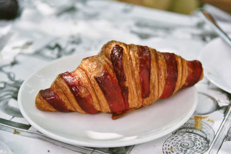 Delicious croissants and ripe berries on a white plate, French breakfast in a cafe.