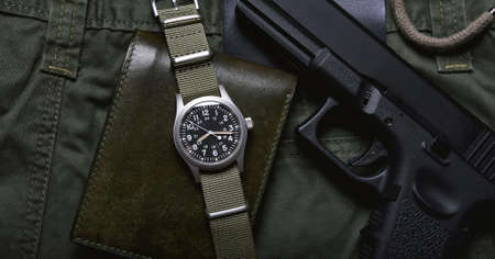 Vintage military watch wallet and pistol on army green background, Classic timepiece mechanical wristwatch, Military men fashion and accessories.の写真素材