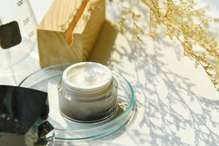 Cosmetic bottle container on sunlight and leaves plant shadow background, Skincare facial cream,...