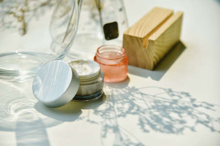 Cosmetic bottle container on sunlight and leaves plant shadow background, Skincare facial cream, Beauty product with warm mood and tone.の写真素材