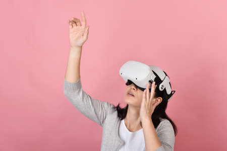 Asian woman using vr glasses, Hand grabbing something from virtual reality headset, Young woman having fun with new experience by vr technology, Studio shot.の写真素材
