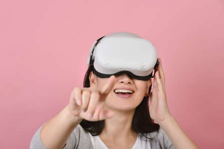 Asian woman using vr glasses, Watching movie and playing video games from virtual reality headset, Young woman amazing with new experience by vr technology, Studio shot.の写真素材