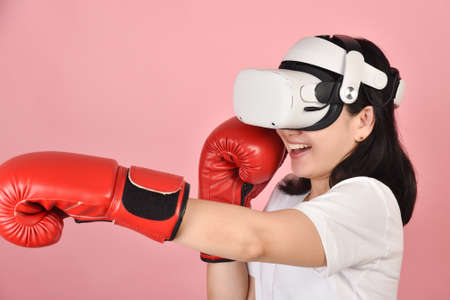 Asian woman hitting a punch by vr glasses, Working out with boxing video games application from...