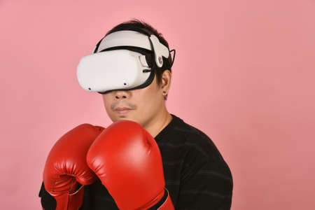 Asian man using vr glasses, Working out with boxing video games application from virtual reality headset, Young man enjoy new fitness experience by vr technology, Studio shot.の写真素材