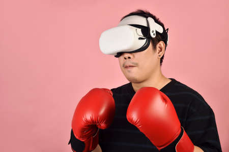 Asian man using vr glasses, Working out with boxing video games application from virtual reality headset, Young man enjoy new fitness experience by vr technology, Studio shot.の写真素材