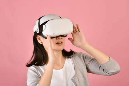 Asian woman using vr glasses, Watching movie and playing video games from virtual reality headset, Young woman amazing with new experience by vr technology, Studio shot.の写真素材