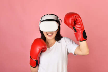 Asian woman using vr glasses, Working out with boxing video games application from virtual reality headset, Young woman enjoy new fitness experience by vr technology, Studio shot.の写真素材