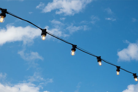Energy-saving light bulbs on a wire, blue sky, a beautiful decoration for the evening city.