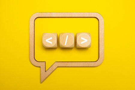 Coding language development icon on yellow background. Software development concept on wooden speech...