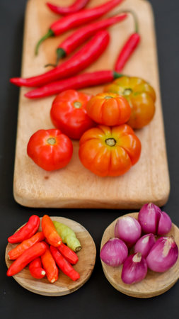 Indonesian chili sauce ingredients isolated on black background. Red chili, shallot, hillbilly tomato, red hot chili pepper.の写真素材