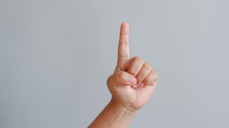 Child's hand pointing finger up on gray background with copy space. counting one concept.の写真素材
