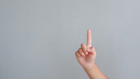 Child's hand pointing finger up on gray background with copy space. counting one concept.の写真素材