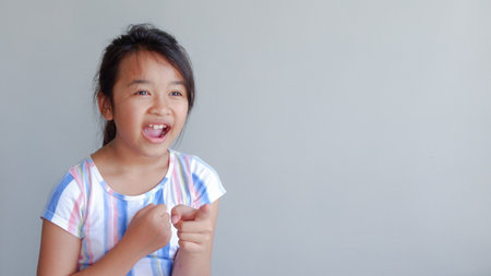 portrait of girl pointing to the forward. isolated on light grey background.の写真素材