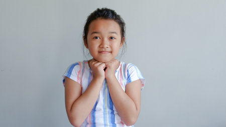 Little asian girl making funny face on gray backgroundの写真素材