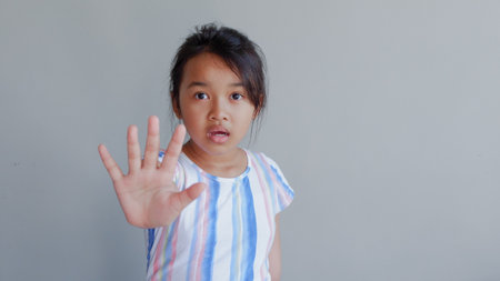 Showing Five Fingers Of Beautiful Asian Child Isolated On Light Grey Background.