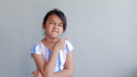 portrait of girl pointing to the forward. isolated on light grey background.の写真素材