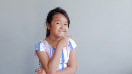 portrait of girl pointing to the side. isolated on light grey background.の写真素材