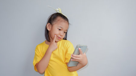 Portrait of a cute little girl grimacing while taking selfie isolated over gray backgroundの写真素材