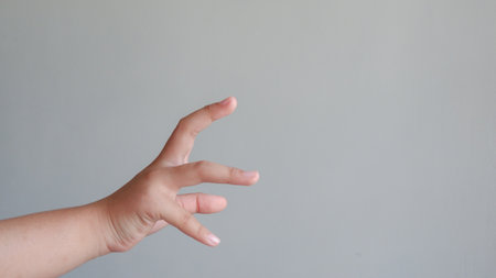 Hand of a child holding something in the air on a gray backgroundの写真素材