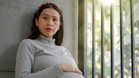 Pregnant asian woman wear grey sweater holding hand on belly. Pregnancy, maternity, preparation and hope concept. Beautiful tender mood pregnancy photo.の写真素材