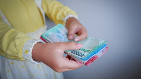 Asian young girl feel happy and holding some money of Indonesian rupiah. Concept of receiving THR on Eid al-Fitr or Lebaran days for muslim.の写真素材