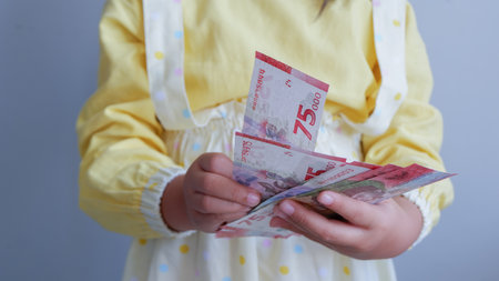 Asian young girl feel happy and holding some money of Indonesian rupiah. Concept of receiving THR on Eid al-Fitr or Lebaran days for muslim.の写真素材