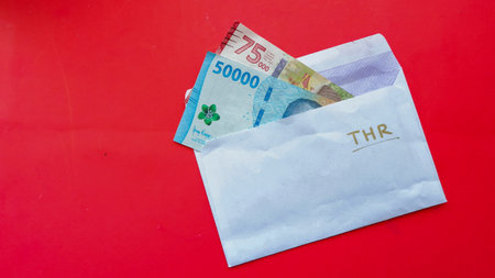 Indonesian money or IDR in the envelope with THR text isolated on red background. THR is holiday allowance in Eid Al-fitr or lebaran dayの写真素材
