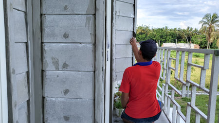 asian man plastering the walls of the houseの写真素材